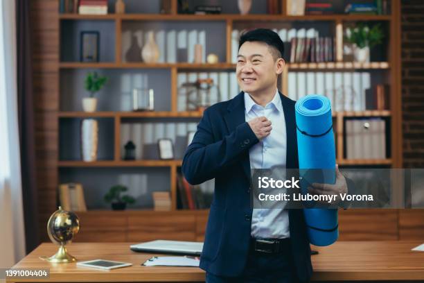 Businessman Has Finished His Working Day And Is Preparing For Fitness Asian Is Working In A Classic Office Late Man Is Holding A Mat For Fitness Stock Photo - Download Image Now