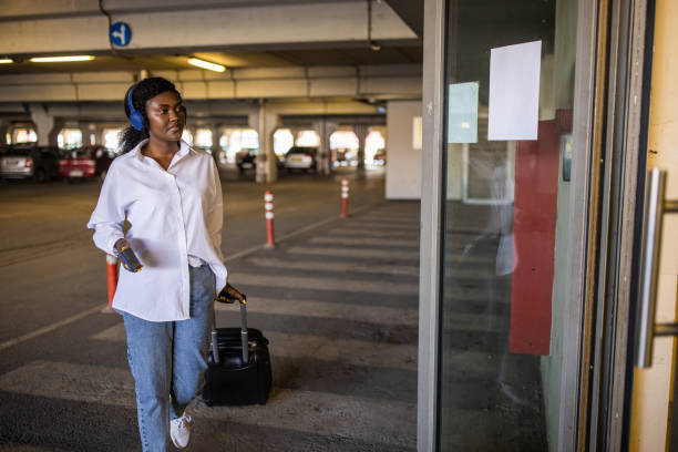 istock Woman Black ethnicity pulling suitcase while using mobile phone at the underground parking lot 1391005068