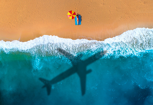 Beautiful  woman sunbathing  at beach. An air plane arriving. Summer holiday beginning concept.