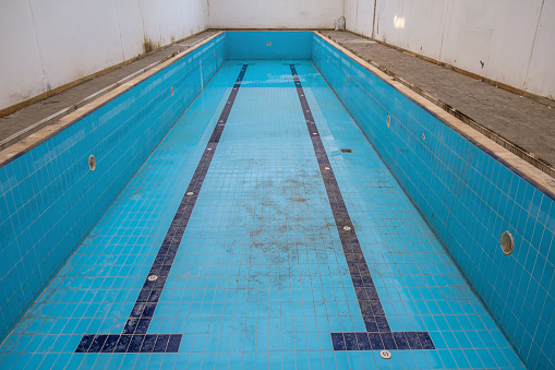 Indoor pool abandoned without care. Blue in color.narrow longitudinal high