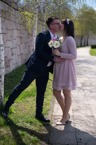 Beautiful pregnant bride and handsome groom kissing portrait outdoor