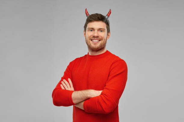 happy man in halloween costume of devil over grey holiday, theme party and people concept - happy smiling man in halloween costume of devil with arms crossed over grey background devil costume stock pictures, royalty-free photos & images