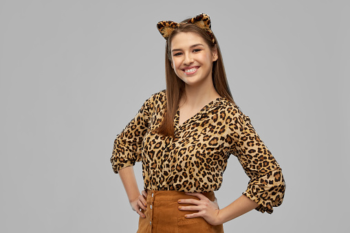 holiday, theme party and people concept - happy smiling woman in halloween costume of leopard with ears over grey background