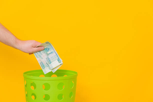 istock A man's hand throws Russian rubles into a trash can, yellow background, side view, space for text. 1391020299
