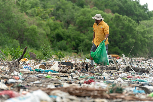 Man picks up plastic garbage on beach in the morning, Panama, Central America.