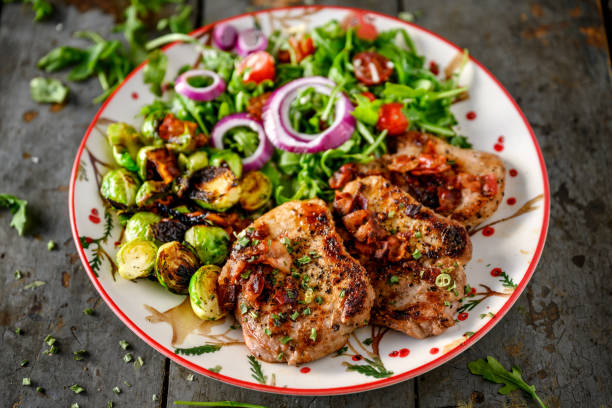 pork chops with brussel sprouts salad - karbonade stockfoto's en -beelden