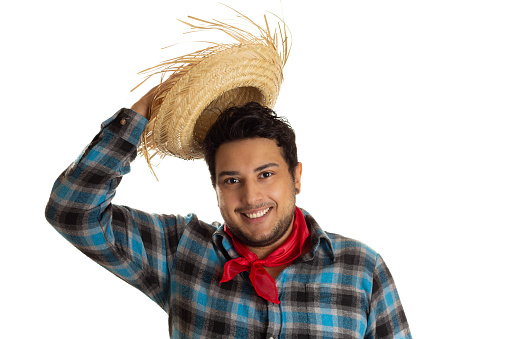 Overweight young man in traditional plaid clothes  is greeting with straw hat. June Festival traditional in Brazil.