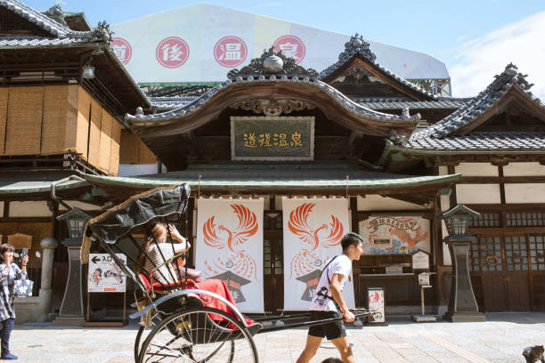 Exterior of Dogo Onsen Honkan Bathhouse and rickshaw stock photo