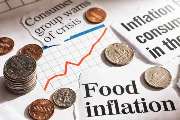 Photo of Inflation hits consumers: newspaper headlines about rising prices with US coins and rising graph