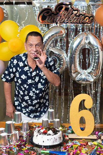 Hispanic Man with number 60 balloons at birthday party