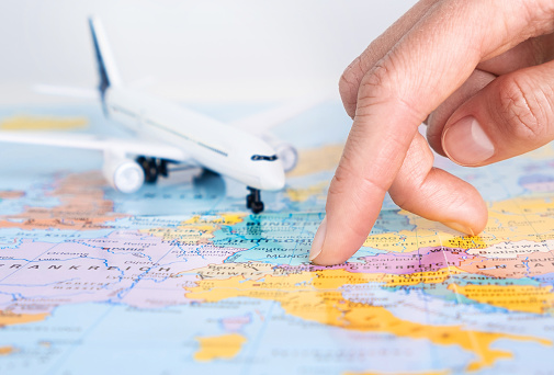 Airplane and finger pointing at map. Flight, travel concept.