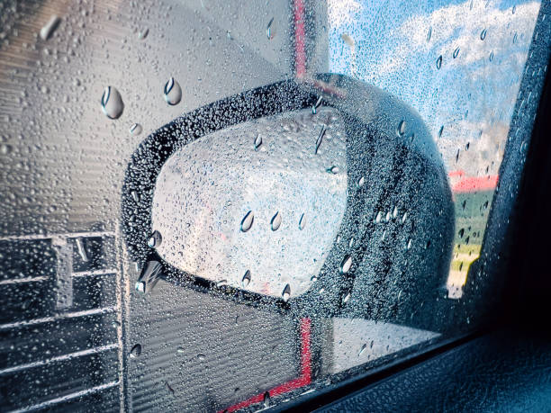 Wet wing mirror in car wash self-service, water drops on glass