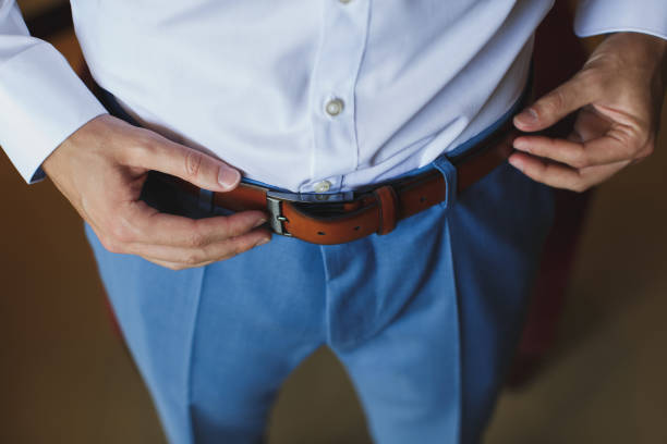 istock Man corrects belt, fees groom, man's hands, dressing, man buttons pants, jeans. 1391044914