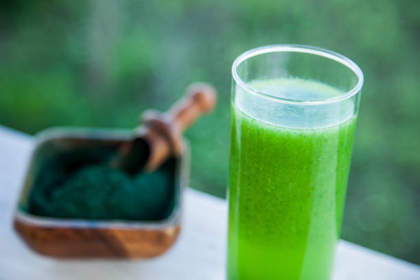 Green smoothie with spirulina on wood background
