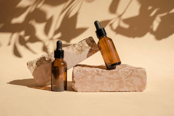 Dark amber glass bottle standing on stone. Natural skin care SPA beauty product design. Mineral organic oil cosmetics on beige background. Mock-Up. Oily pipette. Face and body treatment. Front view Dark amber glass bottle standing on stone. Natural skin care SPA beauty product design. Mineral organic oil cosmetics on beige background. Mock-Up. Oily pipette. Face and body treatment. Front view perfume sprayer photos stock pictures, royalty-free photos & images