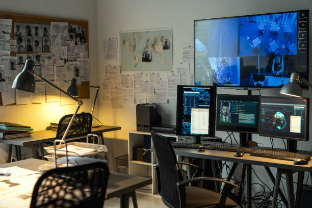 Corner of small office of FBI agency with board and large security camera Corner of small office of FBI agency with set of criminal profiles hanging on board and large screen security camera on wall detective stock pictures, royalty-free photos & images
