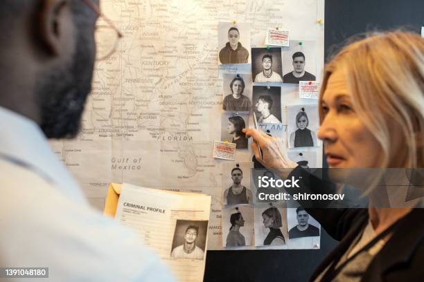 Blond Confident Female Detective Pointing At Photo Of Suspect On Board Stock Photo - Download Image Now