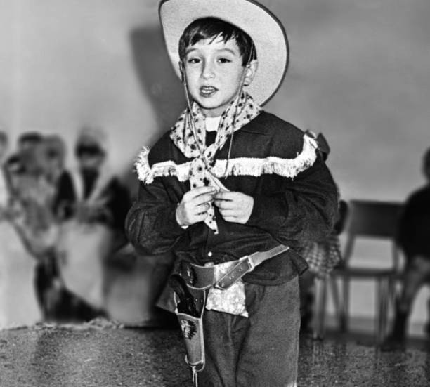 Little boy dressed as cowboy singing at school in 1963.
