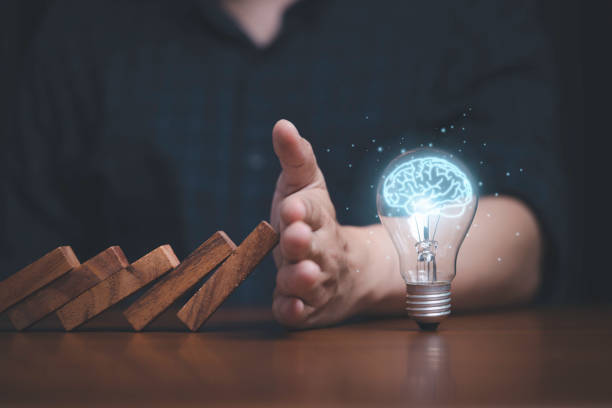 istock Hand protecting lightbulb with glowing virtual brain from falling wooden block , It is symbol of protect copyright and patent concept. 1391051074