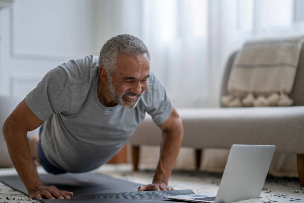 senior gentleman trainiert virtuell zu hause - senior adult healthy lifestyle athleticism lifestyles stock-fotos und bilder