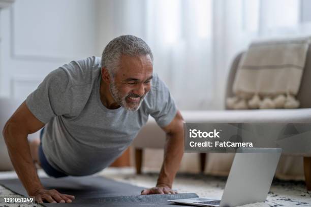 Senior Gentleman Exercising Virtually At Home Stock Photo - Download Image Now - Exercising, Yoga, Relaxation Exercise