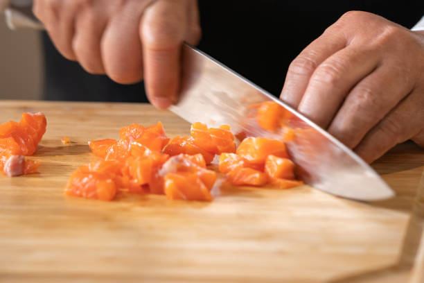 istock Close up to Slicing Cube Salmon by motion movement Knife by Prefessional Chef. 1391054255