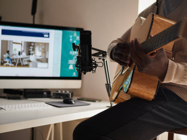 il giovane sta cantando e suonando la chitarra mentre fa una registrazione audio a casa - folk music audio foto e immagini stock