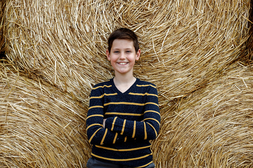 Boy having fun with hay bale in spring