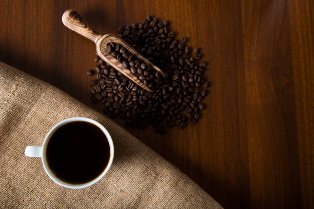 White cup of filter coffee with coffee beans on wooden background