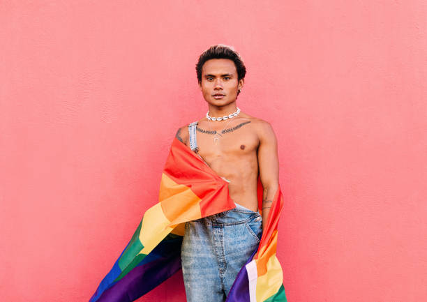 istock Young serious man standing outdoors with rainbow flag 1391059533