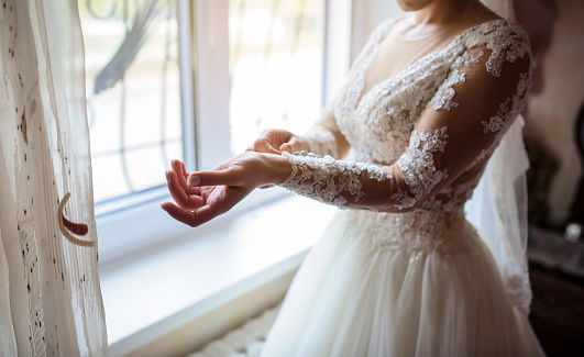 Close up brides hands that arranges her dress