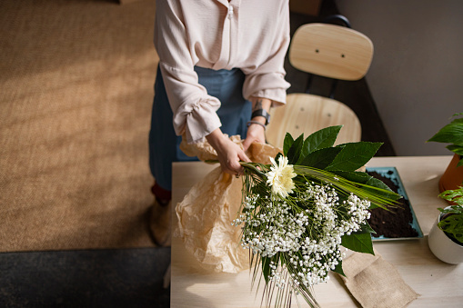 High angle view of an unrecognizable woman taking care of her houseplants, carefully arranging them on the table in her loft apartment