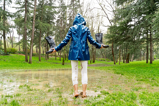 Horizontal panoramic view of woman splashing with mud on rainy pond. Nature and people backgrounds.