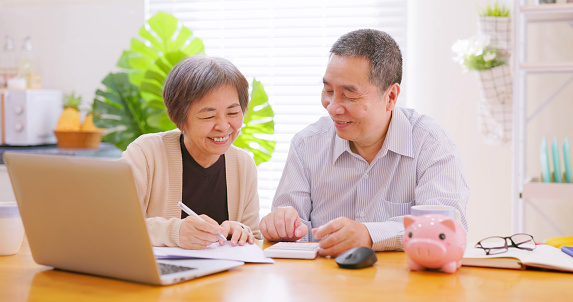Authentic shot of asian elderly couple discuss retirement plan together with laptop and calculator at home happily