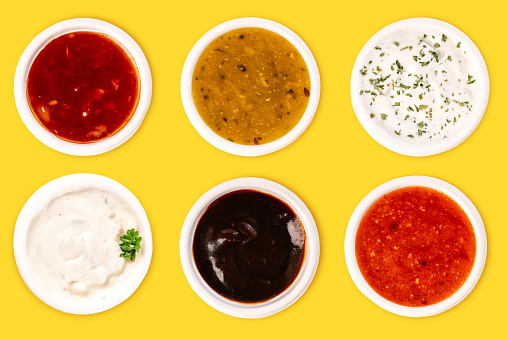 Set of different sauces in ceramic bowl on rustic background