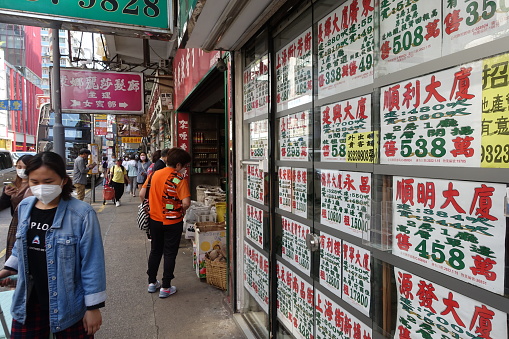 Hong Kong, China - April 06, 2022: City Street View of Mong Kok. Some shop are closed. The People must Wear Mask because of COVID-19.