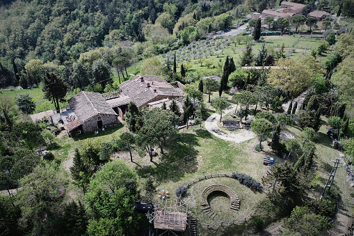 Aerial view of rusty farmhouse amidst trees and plants growing on landscape during sunny day