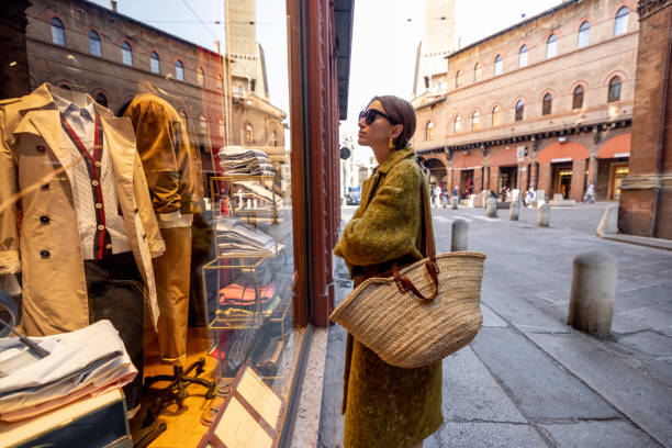 Woman near the showcase of the shop with luxury clothes on street in Bologna Stylish woman stands near the showcase of the shop with luxury clothes on street in Bologna city. Italian style and shopping concept window shopping stock pictures, royalty-free photos & images