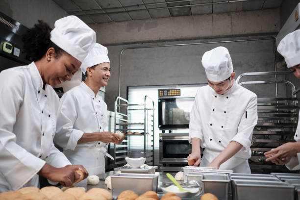 istock Chefs team in uniforms prepare to bake bread and pastry in stainless kitchen. 1391070909