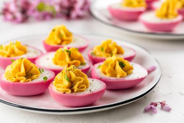 huevos rosados rellenos con pimienta y mayonesa coloreada con remolacha. concepto de comida de pascua, flores de primavera. enfoque selectivo. - deviled fotografías e imágenes de stock