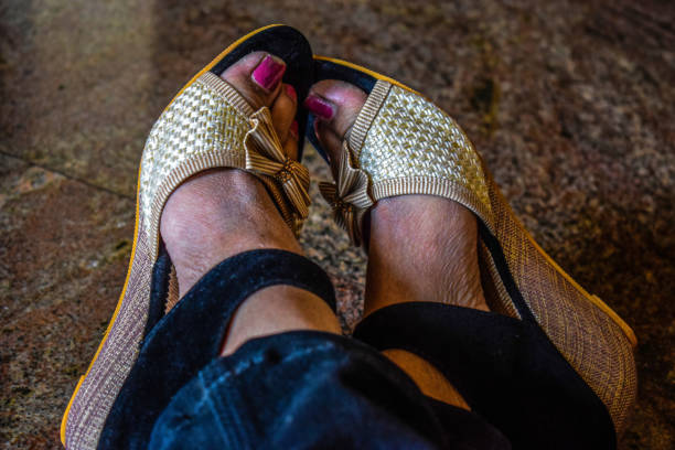 Stock photo of women feet, wearing black and cream color fancy high hell sandal and posing for photo. Picture captured under natural light at Bangalore, Karnataka, India. focus on object. stock photo