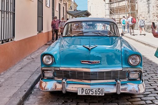 Havana, Cuba - February 14, 2022: Turquoise retro Chevrolet car on narrow paved street of old Havana. Transport, travel concept