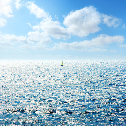 Mediterranean seascape with sailing boat over sunny blue sky