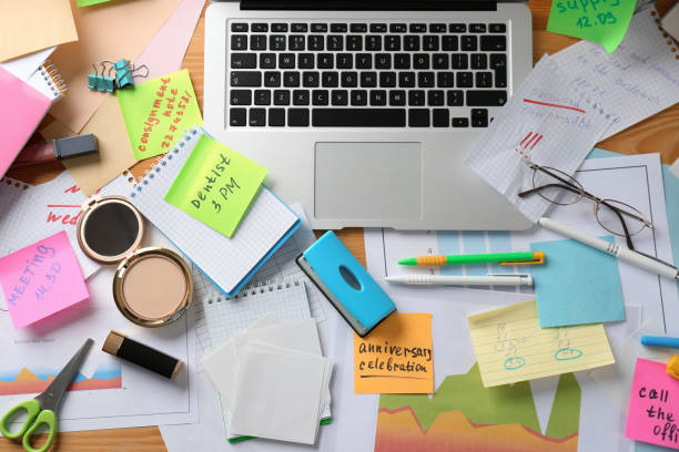 mesa desordenada con computadora portátil y cosméticos, acostada plana. concepto de sentirse abrumado por el trabajo - cluttered desk fotografías e imágenes de stock