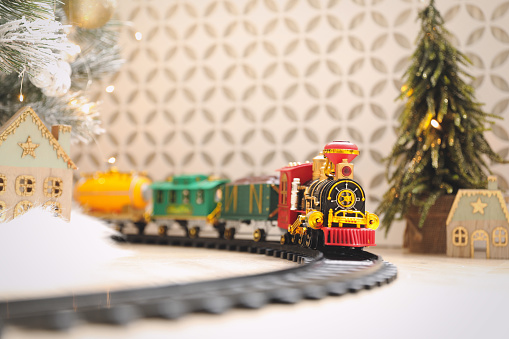 Toy train and railway near Christmas tree indoors