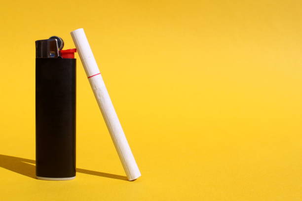istock A white cigarette with a filter rests on a black lighter on a yellow background with space for text. 1391090472