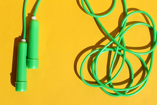 The green jump rope lies on a yellow background.