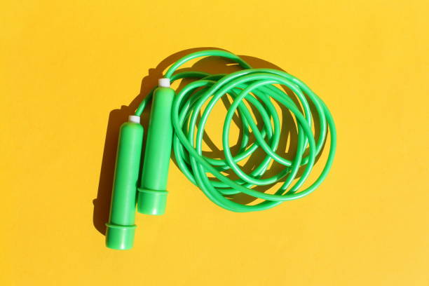 The green jump rope lies on a yellow background. The green jump rope lies on a yellow background. jump rope stock pictures, royalty-free photos & images
