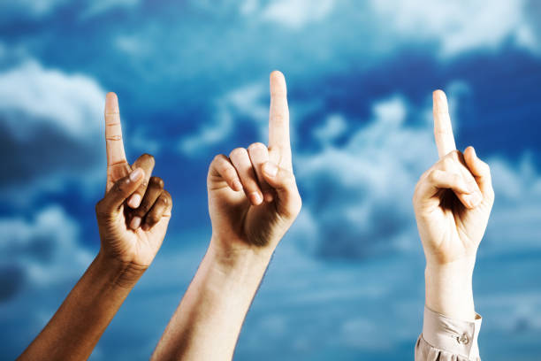 istock Hands with fingers pointing upward, held aloft against a moody sky 1391090600