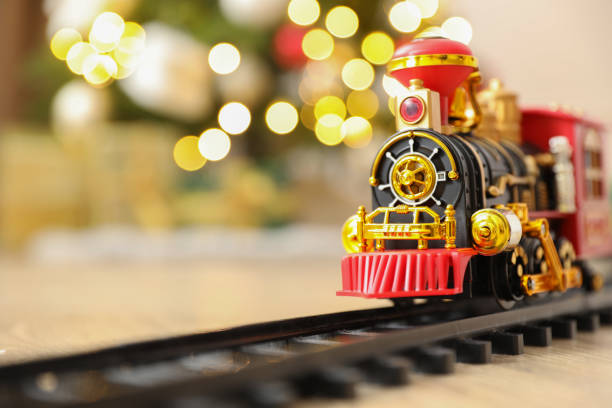 tren de juguete y ferrocarril en el suelo contra las luces de navidad. espacio para texto - tren miniatura fotografías e imágenes de stock